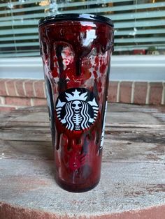 a red starbucks cup sitting on top of a wooden table