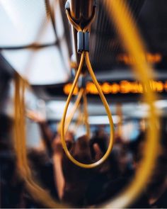 a yellow object hanging from the ceiling in a room with other people and lights behind it