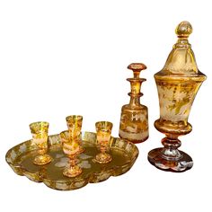 This is an exquisite collection of Bohemian amber cut-to-clear crystal from the nineteenth century, featuring one decanter, on pokal, four cordial glasses and a matching tray. All beautifully hand-carved, etched and acid washed with images of deer in woodland, trees, ferns, leaves and grapevines. The tray is rimmed in vine leaves and the central image depicts a bunch of grapes with leaves and tendrils. Each cordial glass features a unique, individual deer in a woodland scene. The decanter features a stag with large antlers as well as a lovely dog in a woodland, and the pokal features flying birds over large oak trees and more deer. The detail and quality of the carving on these pieces is exceptional. All in near perfect condition: some very light surface scratches to the tray, and a bit of Woodland Trees, Cordial Glasses, Bohemian Crystal, Vine Leaves, Woodland Scene, Crystal Glassware, Grape Bunch, Crystals In The Home, Auction Items