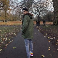 a man standing on a path in a park with trees and leaves all around him