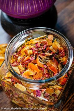 a jar filled with dried fruit sitting on top of a wooden table next to other fruits