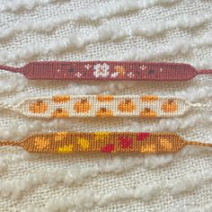 three crocheted beaded bracelets sitting on top of a white blanket next to each other