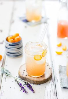 two mason jars filled with lemonade and lavender sprits on top of a wooden board