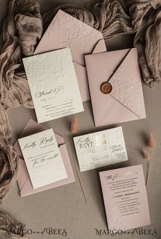 the wedding stationery is laid out on top of each other, including pink envelopes and