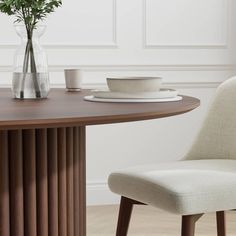 a dining room table with two chairs and a vase filled with flowers