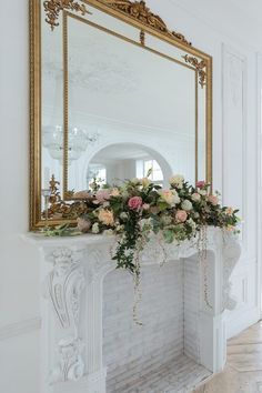 a fireplace with flowers on it and a large mirror above the fire place in front of it