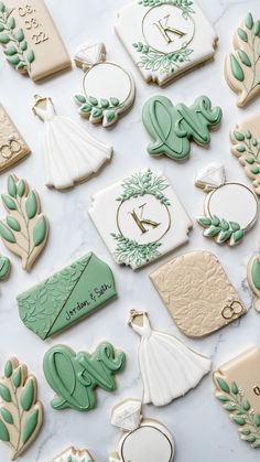 wedding cookies are laid out on a marble counter top with green and white decorations around them