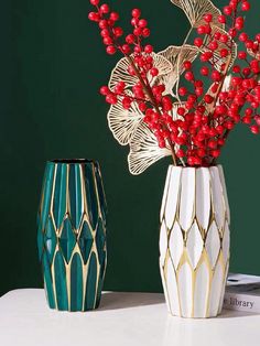 two vases with red berries in them on a table