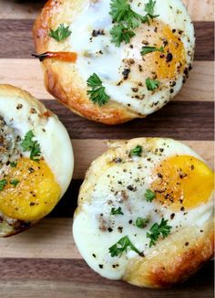 three baked eggs in bread on a cutting board with parsley sprinkled around them