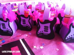 pink and black guitar shaped gift bags on a table