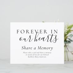 a white card with the words forever in our hearts share a memory on it next to some flowers