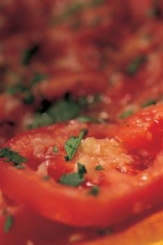 a close up view of tomatoes with herbs on top