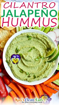 guacamole hummus in a white bowl surrounded by carrots and celery