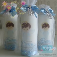 three white candles decorated with blue ribbon and embellishments