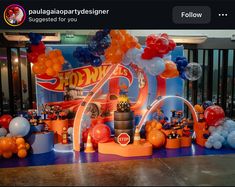 an orange and blue birthday party with balloons on the table, including hot wheels decorations