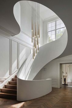 a spiral staircase in the middle of a room with white walls and wood flooring