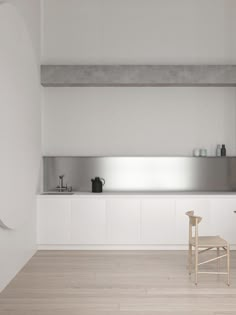 an empty kitchen with white walls and wooden flooring is pictured in this image, there are two chairs next to the counter