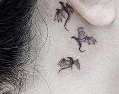 a woman's behind the ear has three small dragon tattoos on it