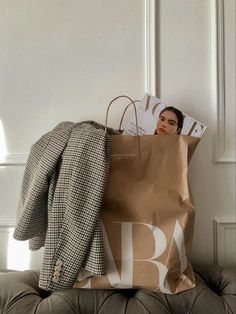 a woman laying on top of a couch with a brown bag over her head and magazine in front of her face