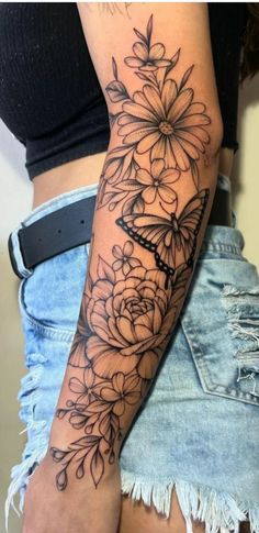 a woman's arm with flowers on it and a clock in the middle of her arm