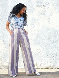 a woman standing in front of a white wall wearing wide legged pants and a t - shirt