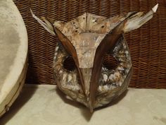 an owl mask sitting on top of a table next to a wicker wallpaper