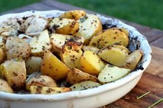 a white bowl filled with potatoes on top of a wooden table