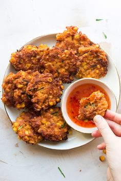 someone is dipping something into a small bowl on a plate with some food in it