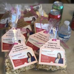 several bags of popcorn with tags on them sitting on a table next to bottles of water