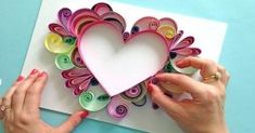 two hands holding a paper heart on top of a card