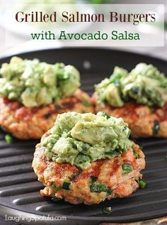 three crab cakes with guacamole on top are sitting on a grill grate