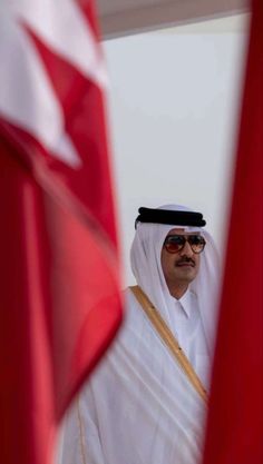 a man standing next to two flags in front of each other on a sunny day