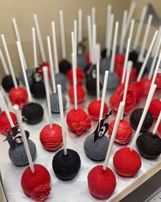 there are many red and black cake pops on the table