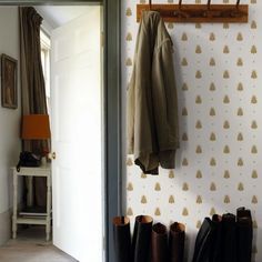 a coat rack with boots hanging on it next to a wallpapered entryway