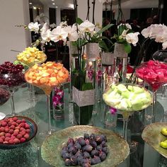 a table topped with lots of different types of fruit and flowers in vases next to each other