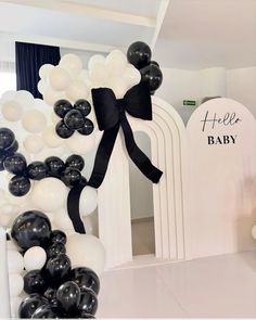 black and white balloons are on display in front of a baby's name sign