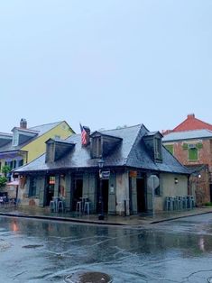 an old building sitting on the side of a road in front of some buildings and umbrellas