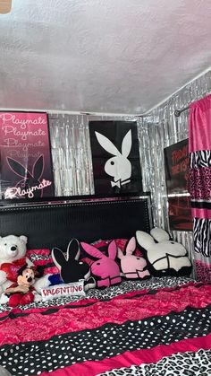 a bedroom with pink and black decor on the walls, stuffed animals in front of the bed