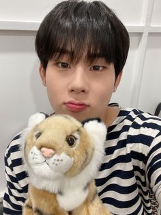 a person holding a stuffed animal in front of their face and looking at the camera