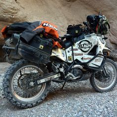 a dirt bike parked on the side of a rocky road next to a rock wall