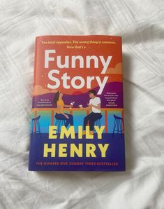 the book funny story is sitting on top of a white bed sheet and it's cover