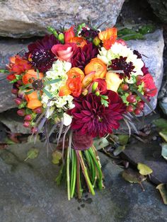 a bouquet of flowers sitting on top of a stone floor next to a rock wall