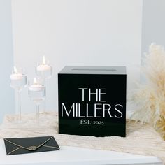 a black box sitting on top of a table next to candles and a card case