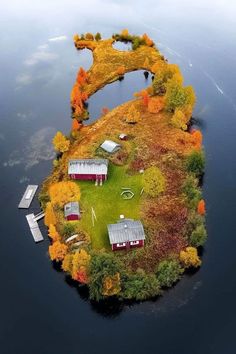 an island in the middle of water with houses and trees on it, surrounded by fall foliage