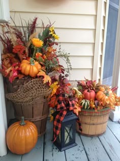 two baskets filled with pumpkins and other autumn decorations on a porch next to a window