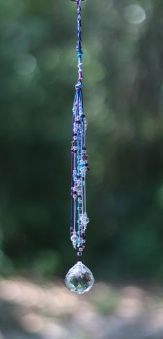 a wind chime hanging from the side of a tree with beads and crystals on it