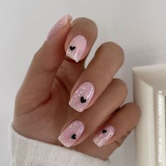 a woman's hand with pink and black nail designs on it, next to a white wall