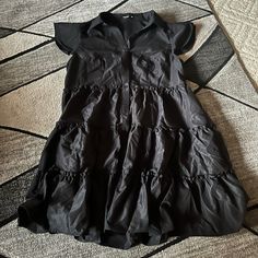 Never Worn Black Dress With Ruffles Going Along The Dress And Buttons! Very Flowy Chic Black Tiered Dress With Ruffles, Black Tiered Dress With Ruffle Hem For Spring, Black Casual Tiered Dress With Ruffles, Black Ruffle Sleeve Dress For Summer, Casual Black Summer Tiered Dress, Casual Black Tiered Summer Dress, Casual Black Ruffle Hem Dress, Casual Black Ruffle Dress, Black Mini Dress With Ruffle Hem For Dress Down