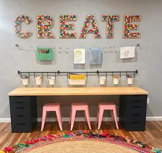 a desk with three stools in front of it and some artwork on the wall