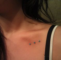 a woman's chest with three small turquoise stones on the top of her chest